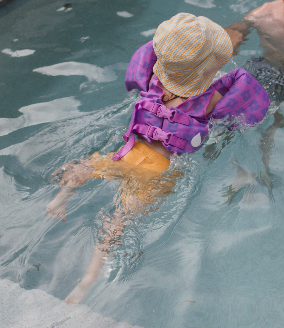 Child wearing a Drip Floats kids swim float while swimming in a pool