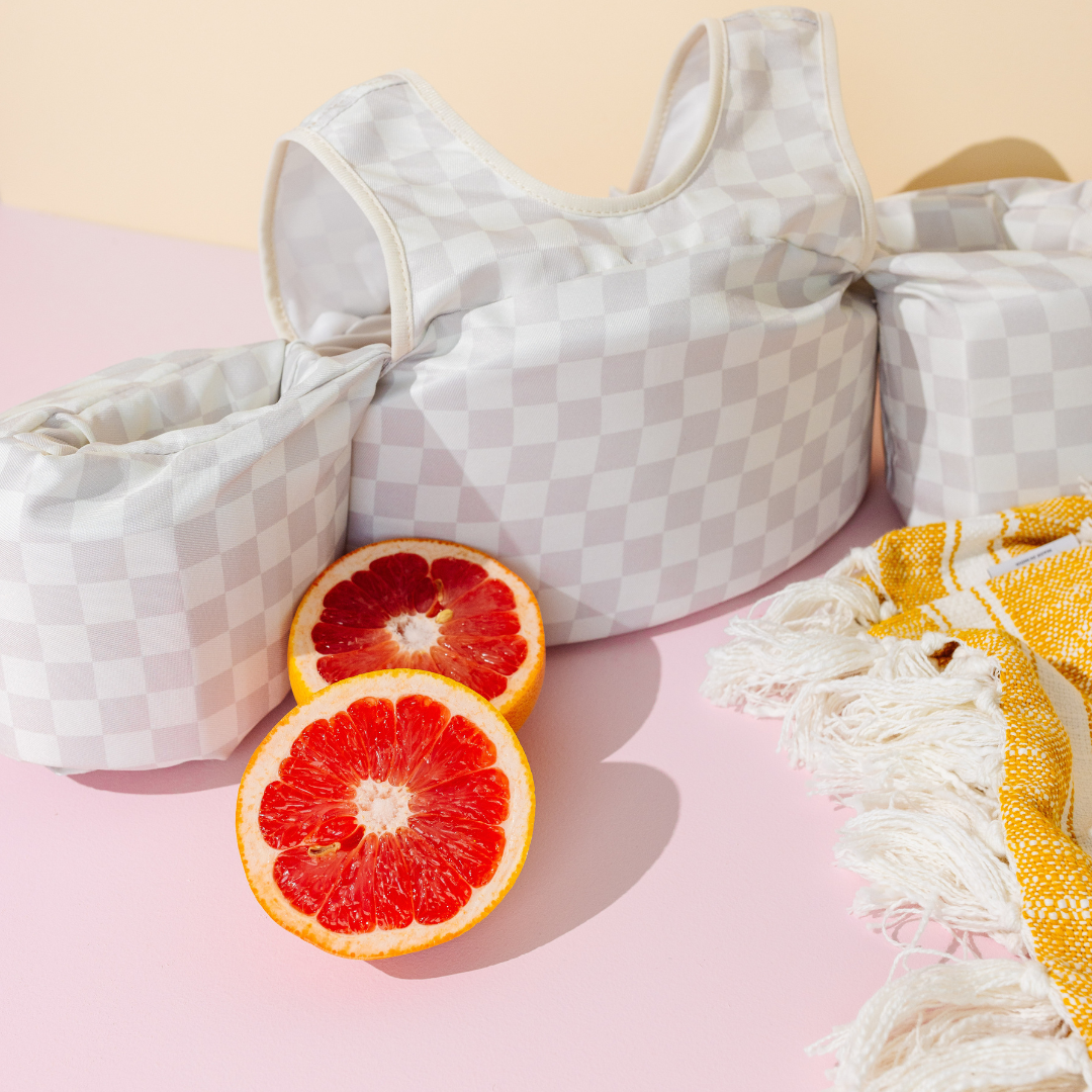 Neutral Checkered Kids Float styled with citrus and a beach towel